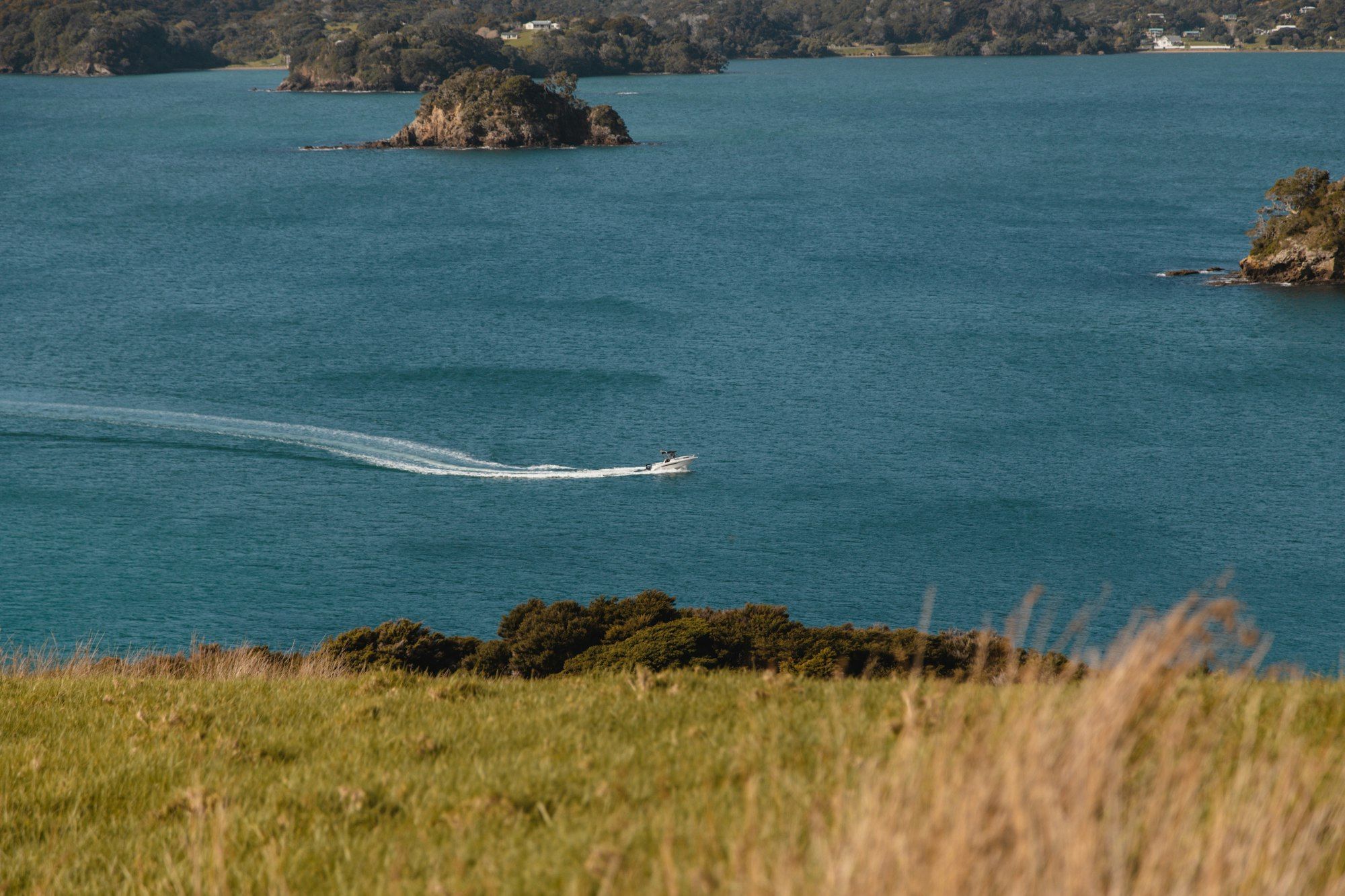A white boat on clear blue water in the Bay of Islands