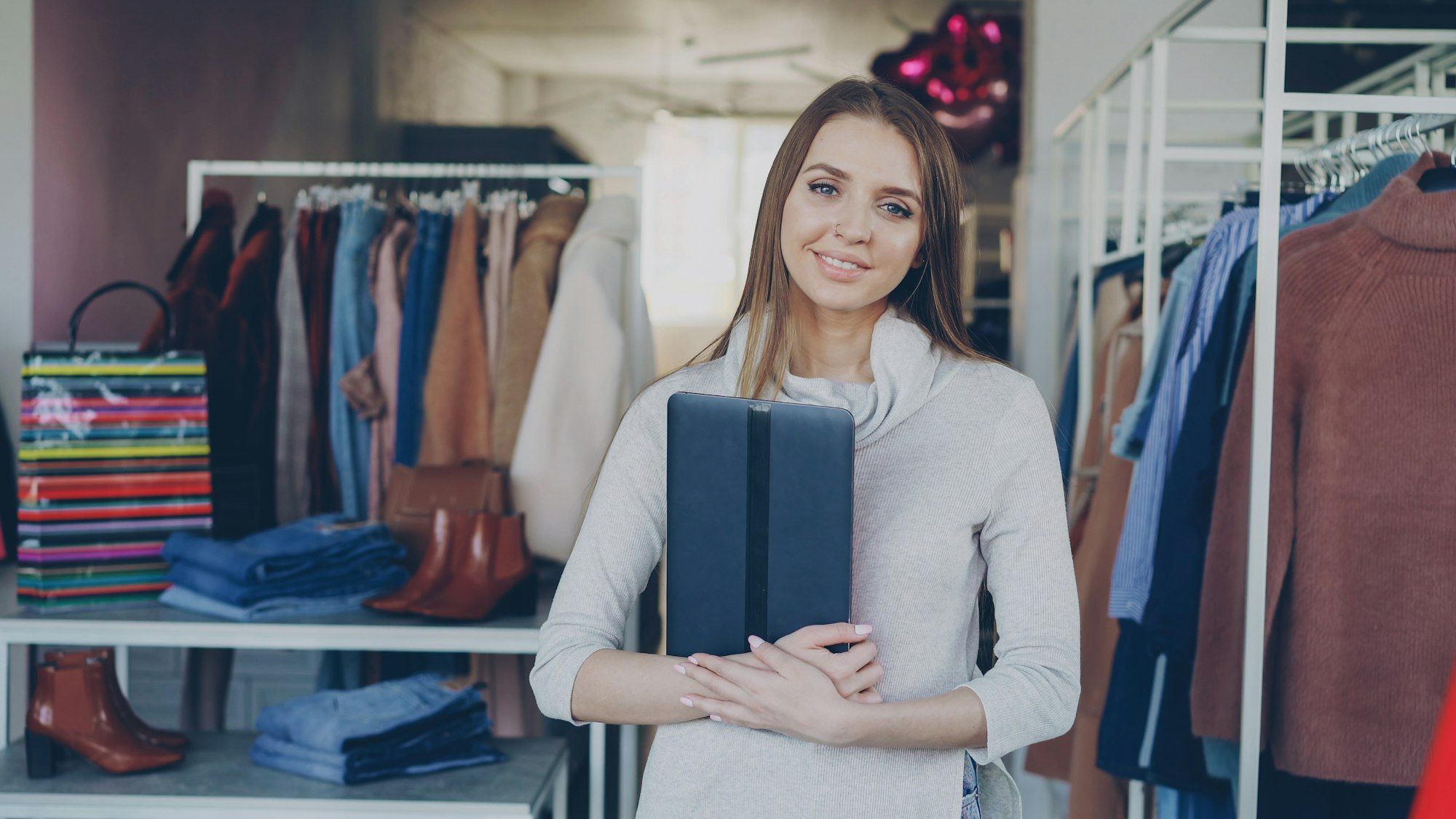 A retailer standing among the racks in her clothing store