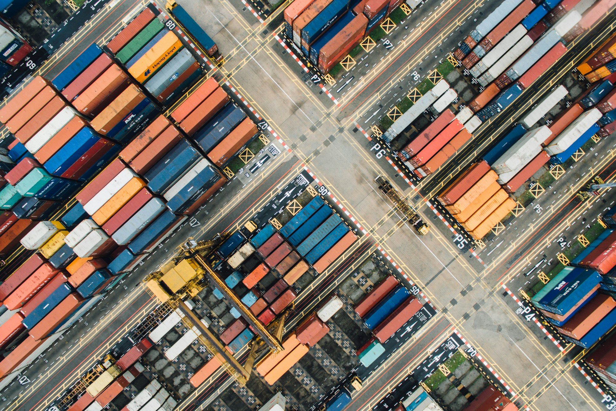 Aerial view of a shipping container yard with rows of coloured containers